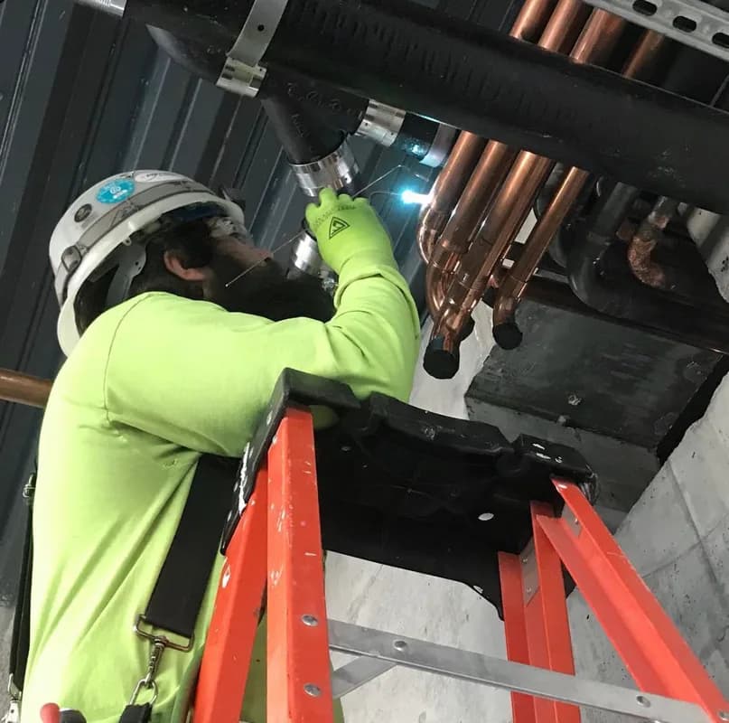 Technician brazing copper refrigerant lines