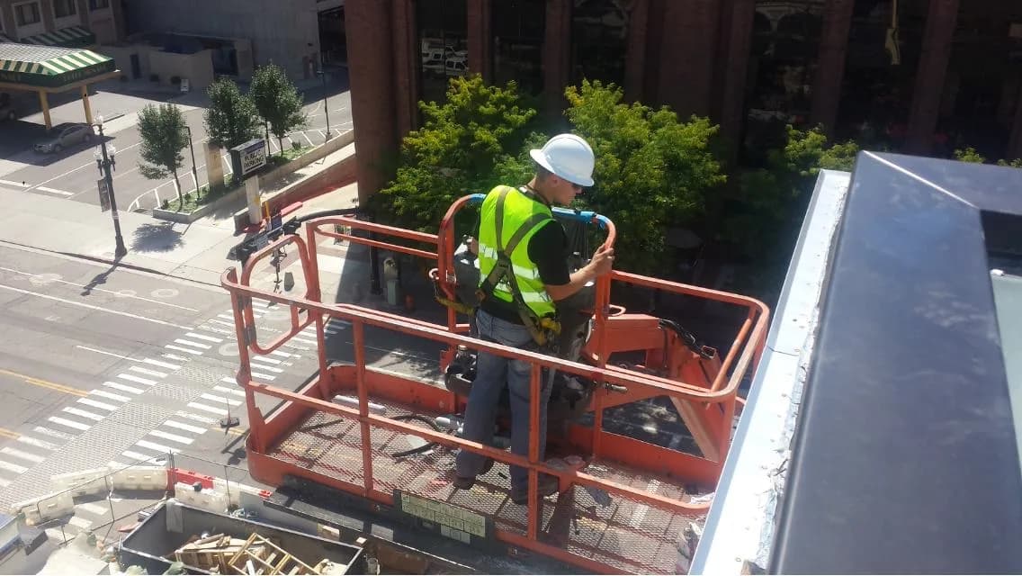 Precision Air technician working on commercial HVAC from a lift